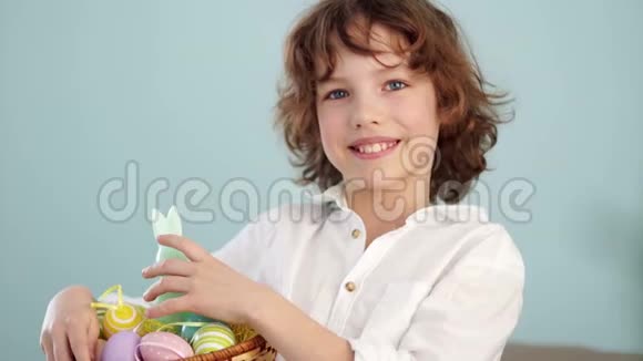 一个孩子拿着一只复活节兔子和一套装饰的复活节彩蛋男孩高兴地笑了慢动作视频的预览图