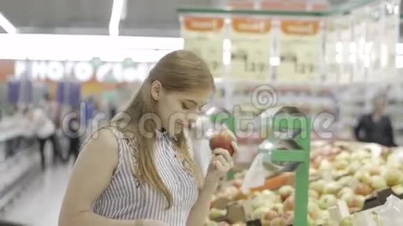 有魅力的年轻女人在超市里选择水果新鲜苹果购物和人的概念股票视频视频的预览图