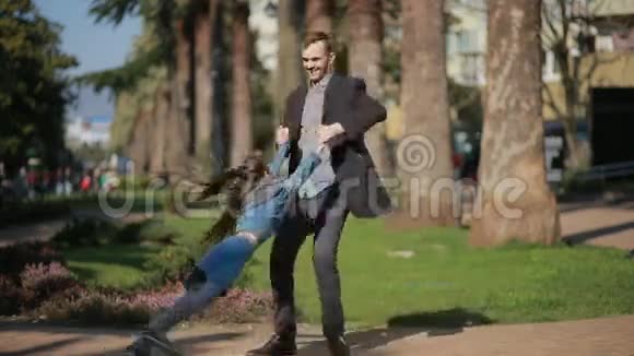 快乐的女儿和爸爸正在公园里散步爸爸正女儿的手旋转视频的预览图