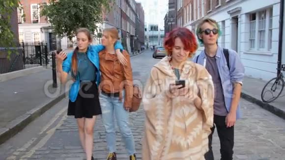 四个朋友正走在伦敦的街道上做自拍嬉笑打闹在暑假视频的预览图
