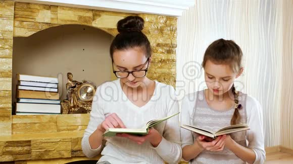姐妹们在家壁炉旁读课本女孩们微笑着拥抱戴着眼镜视频的预览图