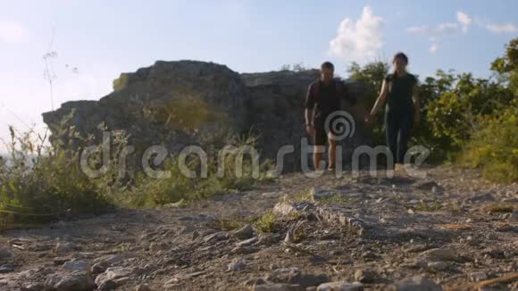 山路一对年轻夫妇在镜头前顶着山顶散步视频的预览图