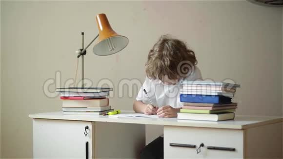 小男孩学习或做家务小男孩用笔记本和书在桌子上学习视频的预览图