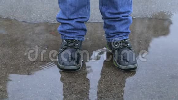 穿着冬靴的男孩在水坑里跳视频的预览图