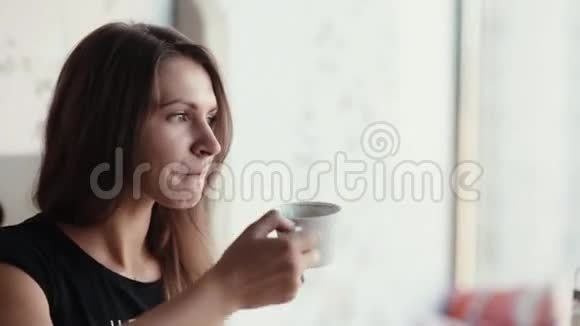 一个棕色头发的漂亮女人的特写脸上有一杯咖啡或茶她说话微笑玩得很开心视频的预览图