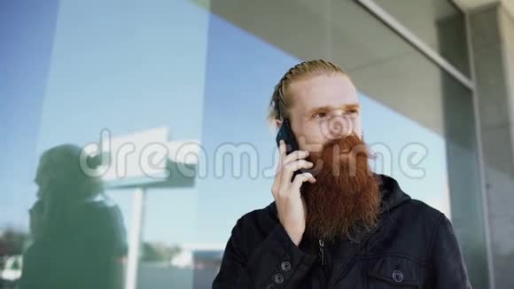 年轻的留胡子的时髦男人集中在城市街上打电话在办公楼附近交谈视频的预览图