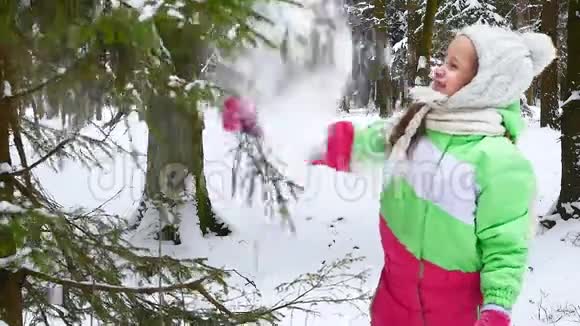 女孩在森林里抖树枝上的雪快乐的童年冬季乐趣视频的预览图