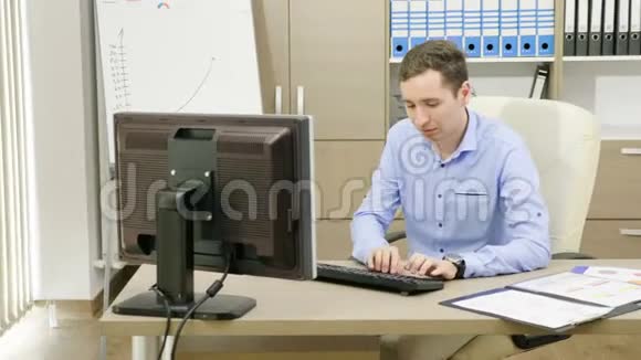 野心勃勃的年轻商人正在他的办公室里工作电脑旁边放着装满图表的文件夹视频的预览图