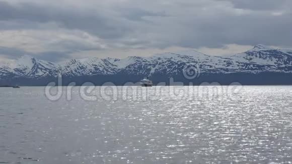 挪威的hurtigruten号船沿海快车在雪山的映衬下夏季驶进特罗姆瑟港视频的预览图