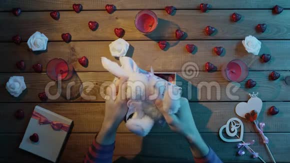 成人将柔软的小兔子放入礼品盒中作为情人节礼物俯视视频的预览图