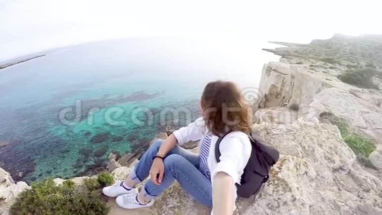 一个背着背包的年轻女子坐在悬崖上视频的预览图