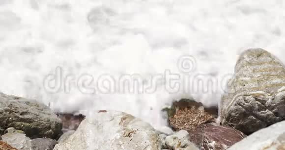 海洋抽象的细节特写岩石在海滩上飞溅产生大量的海洋泡沫海洋抽象背景视频的预览图