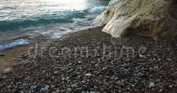 海浪拍打着海滩上的白色岩石沙滩上的沙子石头和鹅卵石缓慢地运动着海景背景视频的预览图
