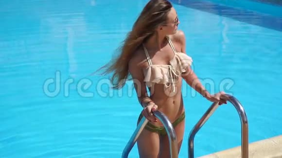 穿着诱人泳装的金发女孩在泳池边摆姿势视频的预览图