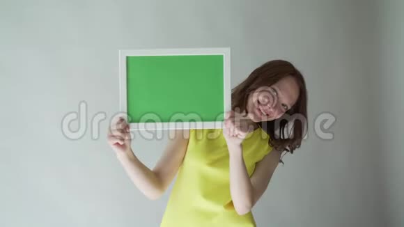 有魅力的女人手里拿着一个彩色的标志在灰色的背景上视频的预览图