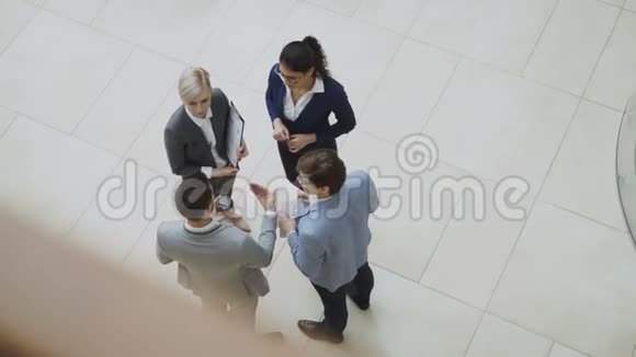 一群西装革履的商务人士在室内商务中心大厅讨论财务图表的俯视图视频的预览图
