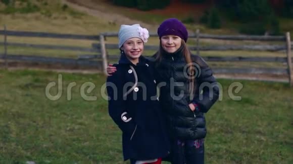 两个漂亮的小女孩拥抱着看着相机在户外微笑着视频的预览图