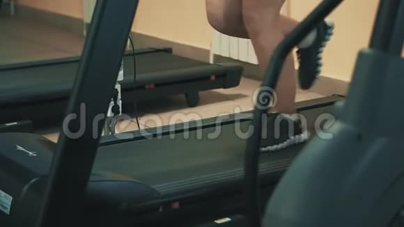 在运动健身中心的跑步机上行走的妇女视频的预览图