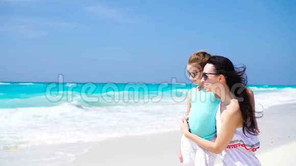 在白沙上享受家庭乐趣阳光明媚的一天微笑的母亲和可爱的孩子在沙滩上玩耍视频的预览图