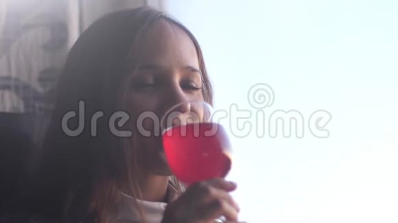 孤独的漂亮女孩正在喝红酒坐在窗边慢动作3840x2160视频的预览图