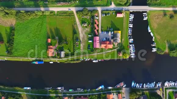 靠近河边的村庄阳光明媚的夏日无人机摄像机垂直倾斜在河边的小村庄上视频的预览图