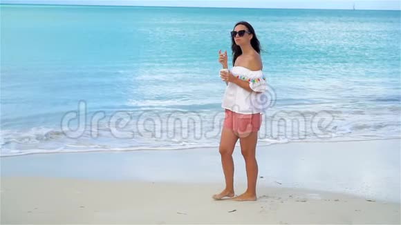 在白色的热带海滩上喝热咖啡的年轻女人流动人口视频的预览图