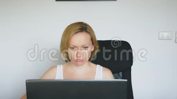 一个女人用她的笔记本电脑坐在桌子旁愤怒和愤怒发誓人类的情感网络成瘾的概念视频的预览图