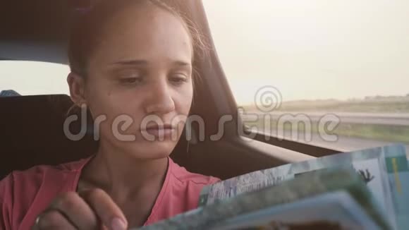 日落时分漂亮的黑发女人在车里看书慢动作3840x2160视频的预览图