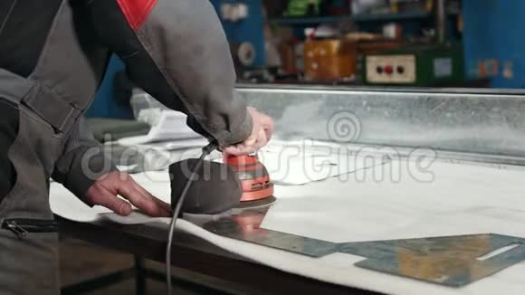 在工厂由一名工人控制的手动砂光机的特写并对金属部件进行砂光处理视频的预览图