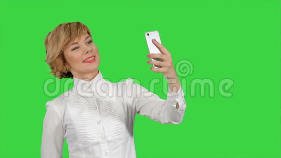 女商人在绿色屏幕上用手机拍摄有趣的自拍色度键视频的预览图