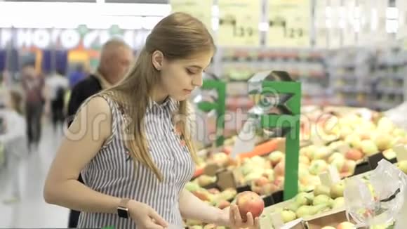 有魅力的年轻女人在超市里选择水果新鲜苹果购物和人的概念股票视频视频的预览图