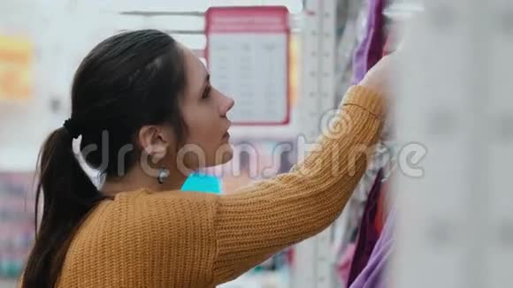 在一家超市里特写年轻女人的脸女孩在货架上挑选衣服脸上带着体贴的表情4K视频的预览图