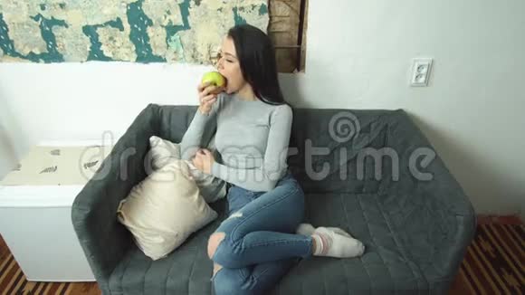坐在客厅沙发上吃苹果的漂亮女孩视频的预览图