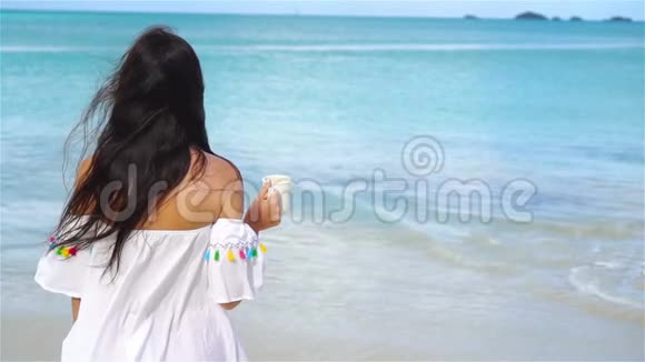 在白色的热带海滩上喝热咖啡的年轻女人流动人口视频的预览图