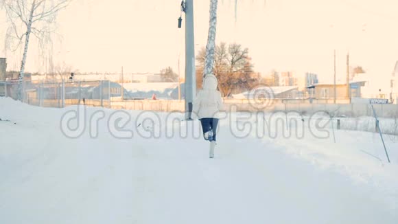 穿着白色外套的女孩在雪地公园慢动作跑视频的预览图