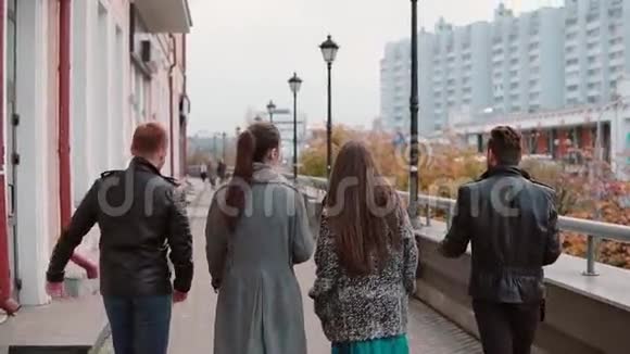 两个时髦的女孩和两个时髦的男人兴高采烈地在城市里散步跳起来玩得很开心慢影稳拍后景视频的预览图