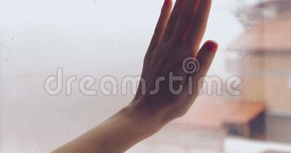 在下雨天的特写镜头中用手擦拭蒸汽窗户视频的预览图