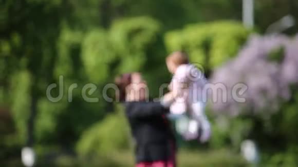 阳光明媚的日子公园里快乐的母亲和可爱的女婴模糊的形象视频的预览图