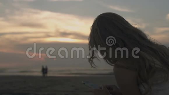 在海滩用电话的女人视频的预览图