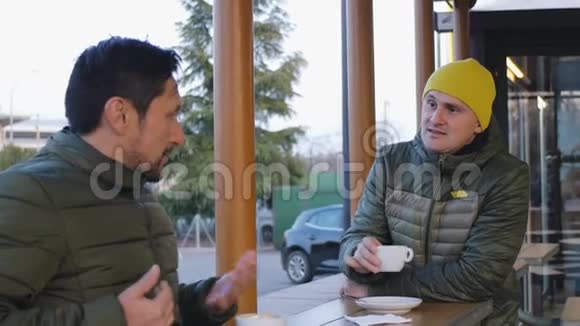 晚上两名穿暖气泡夹克的男运动员在咖啡馆的室外训练后交谈那个家伙视频的预览图