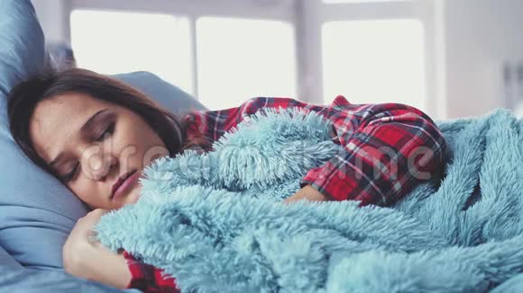 熟睡的年轻漂亮的女人躺在床上醒来伸展和微笑模糊的窗户在背景上慢动作视频的预览图