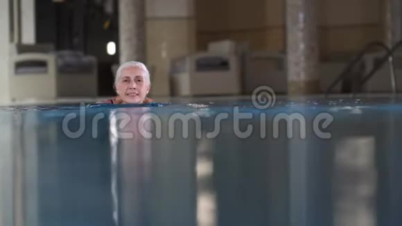 酒店游泳池游泳的漂亮老年妇女视频的预览图
