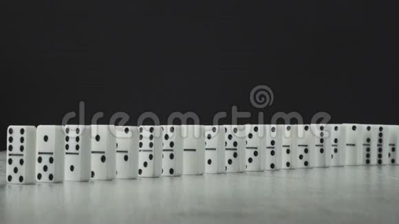 多米诺效应一系列多米诺骨牌掉落在木桌上背景黑色视频的预览图