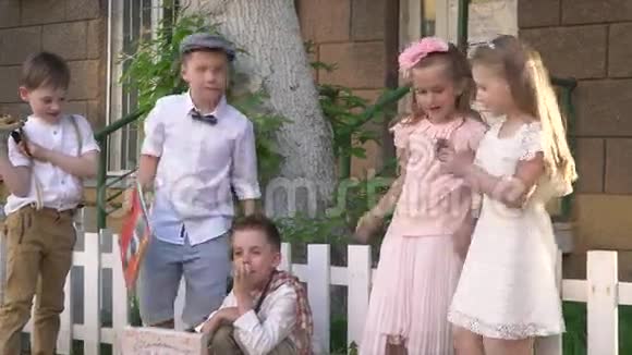 漂亮可爱的孩子们穿着复古的衣服谈论着把肘部靠在篱笆上视频的预览图