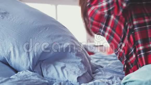 睡眼的年轻黑发女人穿着睡衣慢慢地躺在她房间靠窗的床上一个女孩和视频的预览图