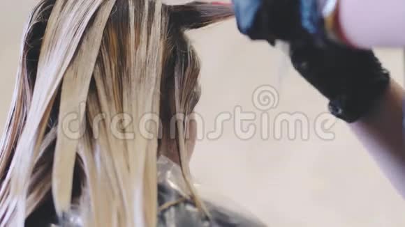 发型师做染发发烫她用刷子近景理发师他的手戴黑手套视频的预览图