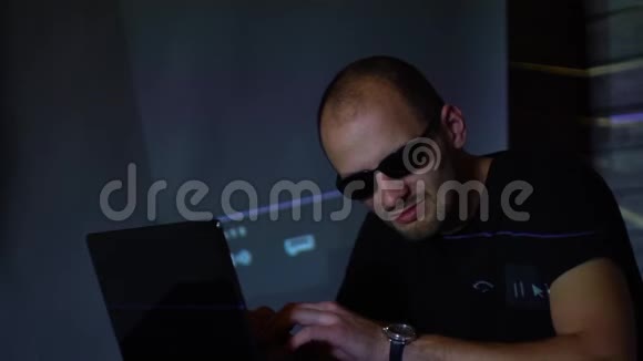 一个戴太阳镜的黑客在黑暗的房间里使用程序代码视频的预览图