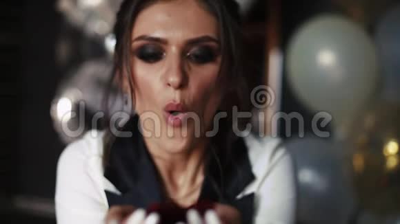 美丽时尚的女人用手在镜头前吹红纸屑视频的预览图