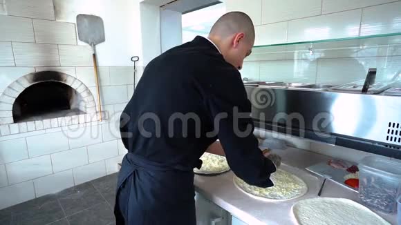 一个年轻的披萨师在餐厅的厨房准备披萨厨师把香肠放进披萨里视频的预览图
