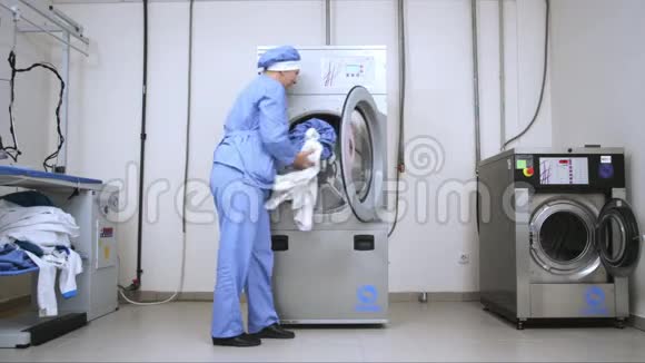 女员工在酒店洗衣店装洗衣机商业洗衣房视频的预览图